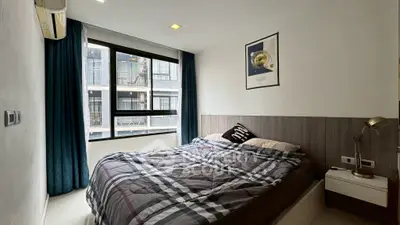 Cozy bedroom with large window and modern decor in urban apartment.