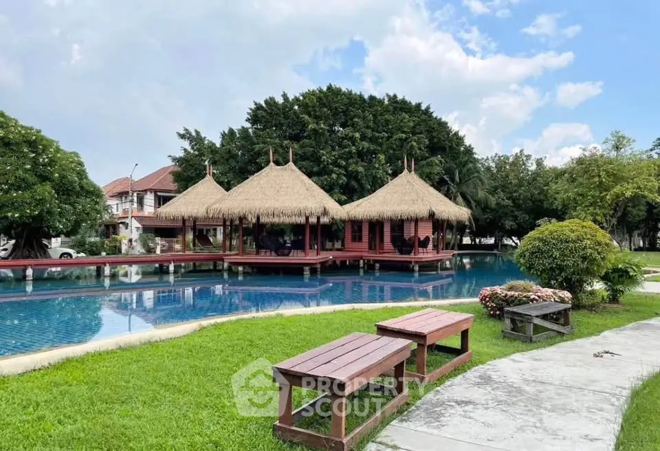 Stunning outdoor pool area with traditional thatched-roof pavilions and lush greenery, perfect for relaxation.