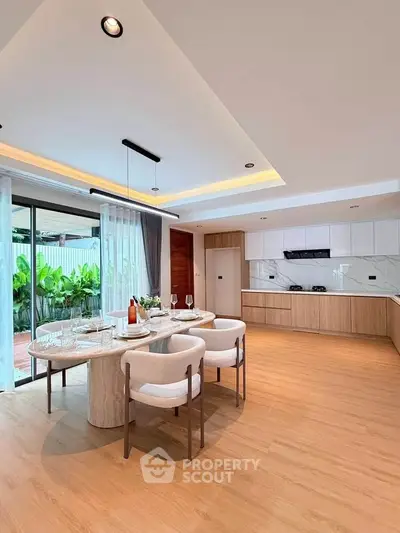 Spacious modern kitchen with open layout and elegant dining area, featuring sleek cabinetry and large windows.