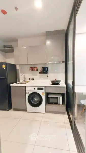 Modern kitchen with sleek appliances and washing machine in compact layout