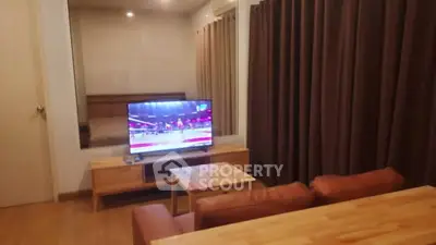 Cozy living room with modern TV setup and warm wooden furniture.