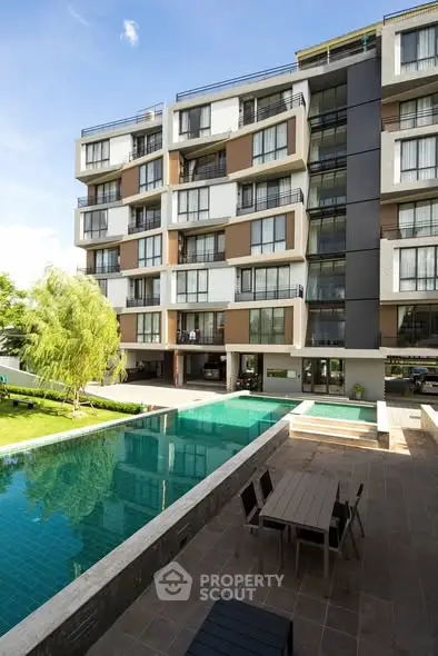 Modern apartment building with pool and outdoor seating area, perfect for luxury living.