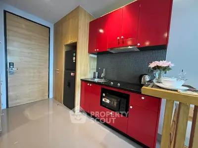 Modern kitchen with vibrant red cabinets and sleek appliances in a stylish apartment.