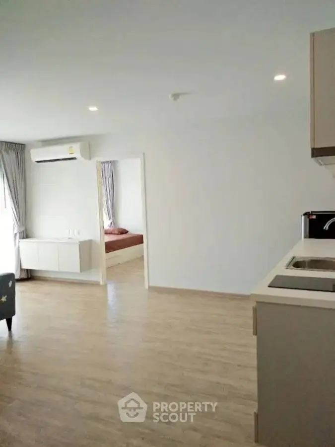 Spacious open-plan living area with modern kitchen and cozy bedroom view.