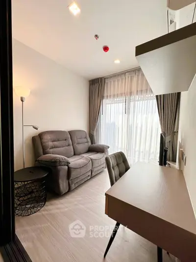 Modern living room with cozy sofa and study desk, featuring large windows and elegant curtains.