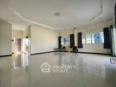 Spacious living room with large windows and glossy tiled floors in modern home.