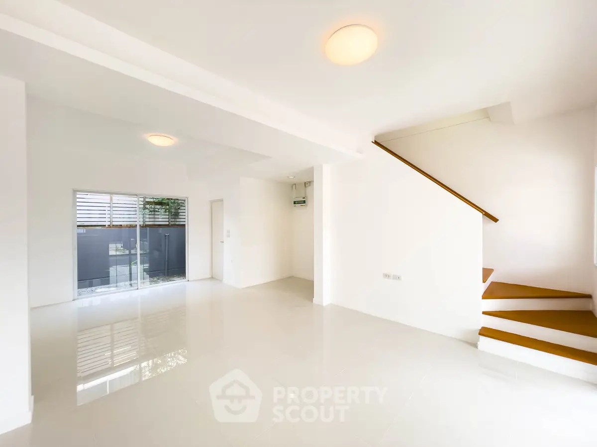 Spacious modern living room with sleek staircase and large windows for natural light.