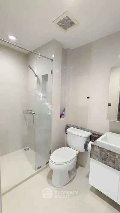 Modern bathroom with glass shower and sleek fixtures in a contemporary apartment.