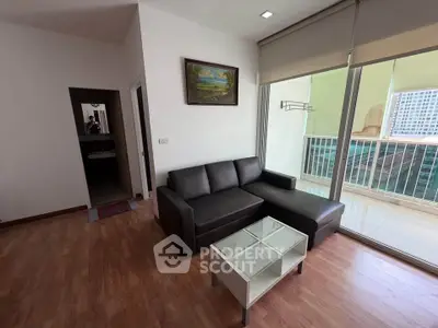 Modern living room with sleek black sofa and glass coffee table, featuring a balcony view.
