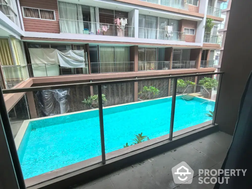 Modern apartment balcony overlooking a pristine swimming pool in a stylish residential complex.