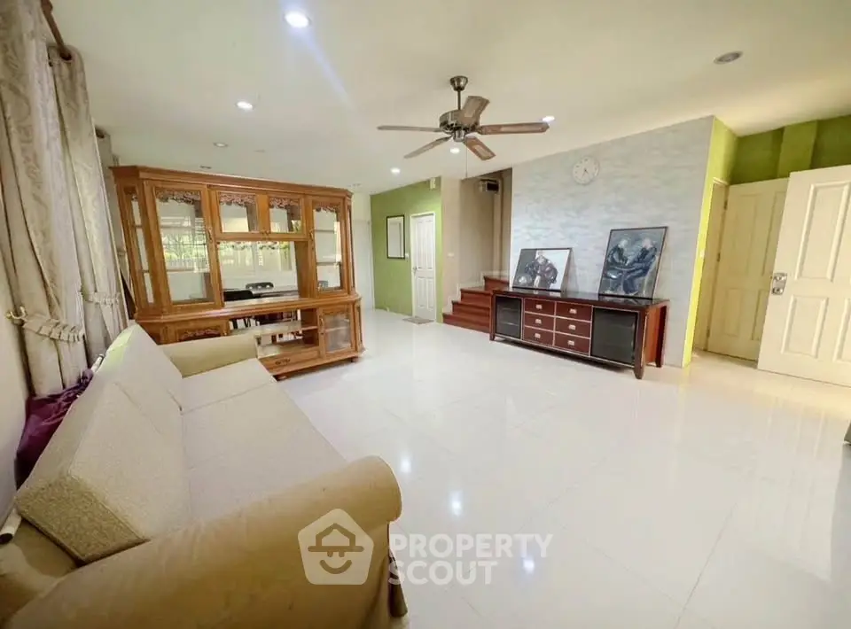 Spacious living room with elegant furniture and ceiling fan, perfect for family gatherings.
