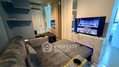 Modern living room with plush gray sofa and large TV, featuring sleek design and cozy ambiance.