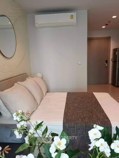 Modern bedroom with stylish decor and air conditioning, featuring a cozy bed and elegant wall mirror.