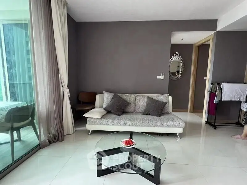 Modern living room with stylish sofa and glass coffee table, featuring a balcony view.