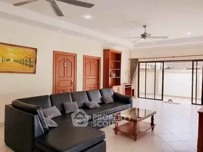 Spacious living room with modern black sofa and sliding glass doors leading to patio.