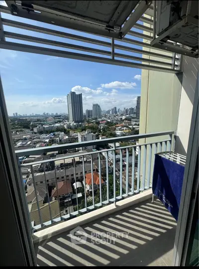 Stunning cityscape view from a high-rise balcony with modern railing and clear blue sky.
