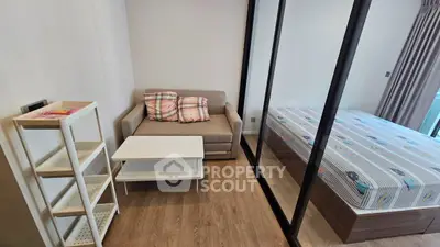 Cozy studio apartment with modern furnishings and wooden flooring, featuring a compact living area and comfortable bed.