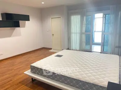 Spacious bedroom with wooden flooring and large windows for natural light