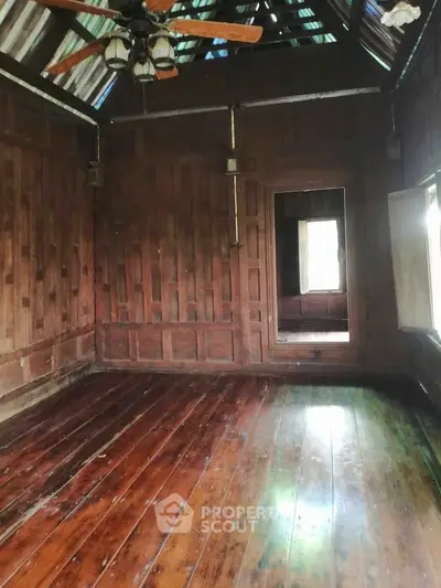 Charming rustic wooden interior with polished floors and ceiling fan, perfect for cozy living.