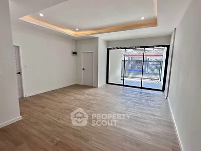 Spacious modern living room with wooden flooring and large window for natural light.