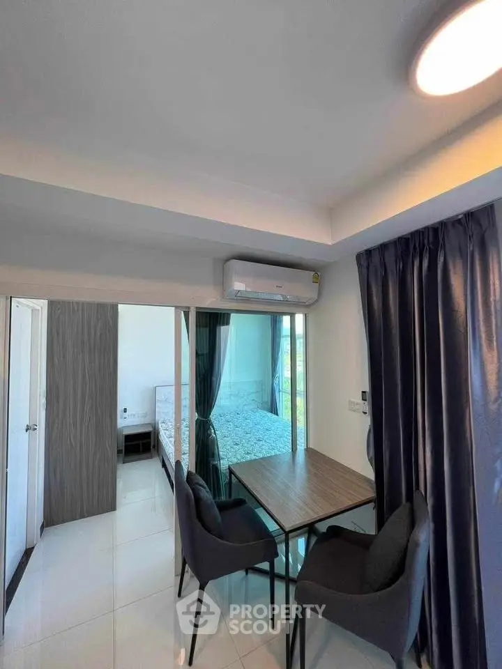 Modern dining area with sleek table and chairs, adjacent to a cozy bedroom with natural light.