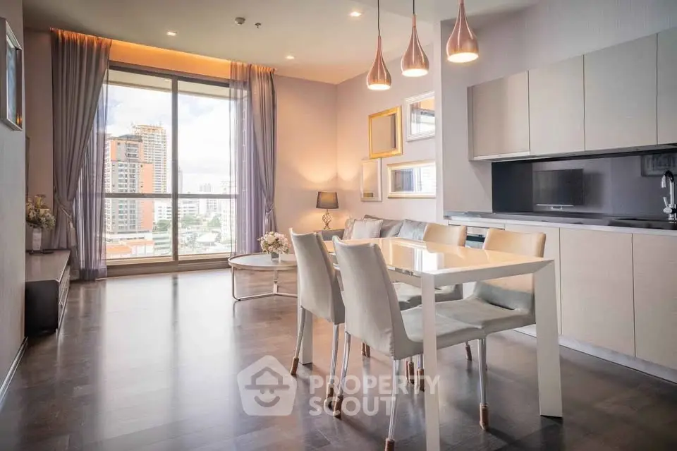 Modern open-layout living room with dining area and city view, featuring elegant lighting and contemporary furnishings.
