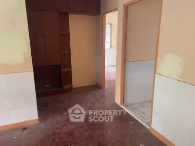 Spacious interior with wooden flooring and built-in shelving, ideal for renovation.