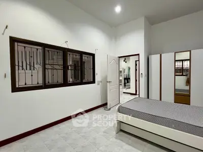 Spacious bedroom with modern design and ample natural light, featuring a large window and sleek wardrobe.