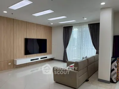 Modern living room with sleek design and large TV, featuring elegant curtains and a comfortable sofa.