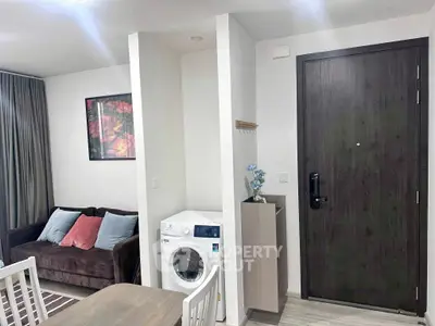 Modern apartment interior with cozy living area and washing machine near entrance.