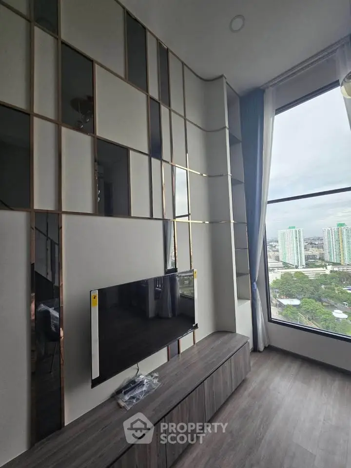 Modern living room with large windows and city view, featuring stylish wall design and sleek TV setup.