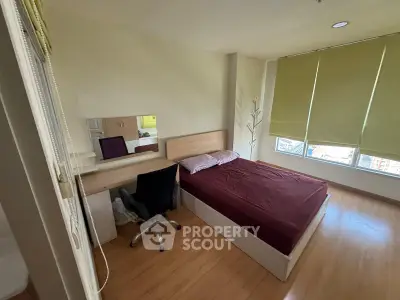 Cozy bedroom with large window and modern furnishings in a stylish apartment.