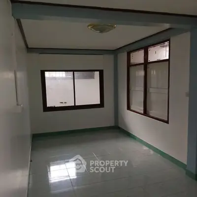 Spacious empty room with large windows and tiled flooring