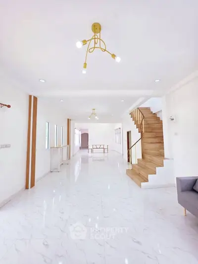 Spacious modern living room with elegant lighting and wooden staircase, perfect for family gatherings.