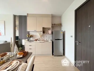 Modern kitchen with sleek cabinetry and stainless steel fridge in open-plan apartment.