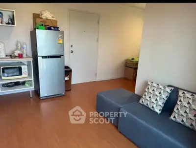 Cozy living room with modern furniture and compact kitchen appliances.