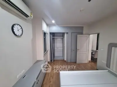 Modern bedroom with open closet and air conditioning, featuring sleek design and wooden flooring.