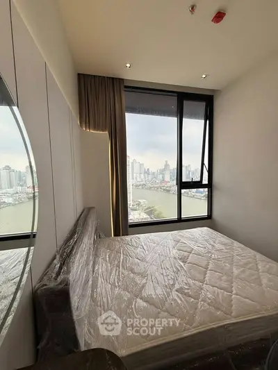 Modern bedroom with stunning city view and large window, featuring a cozy bed and elegant decor.