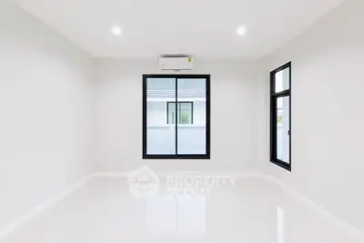 Spacious empty room with large windows and air conditioning unit.