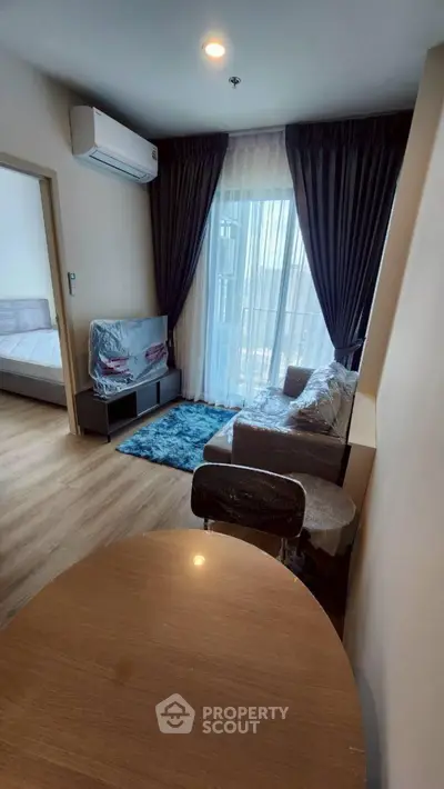 Modern living room with cozy furniture and natural light from large windows.