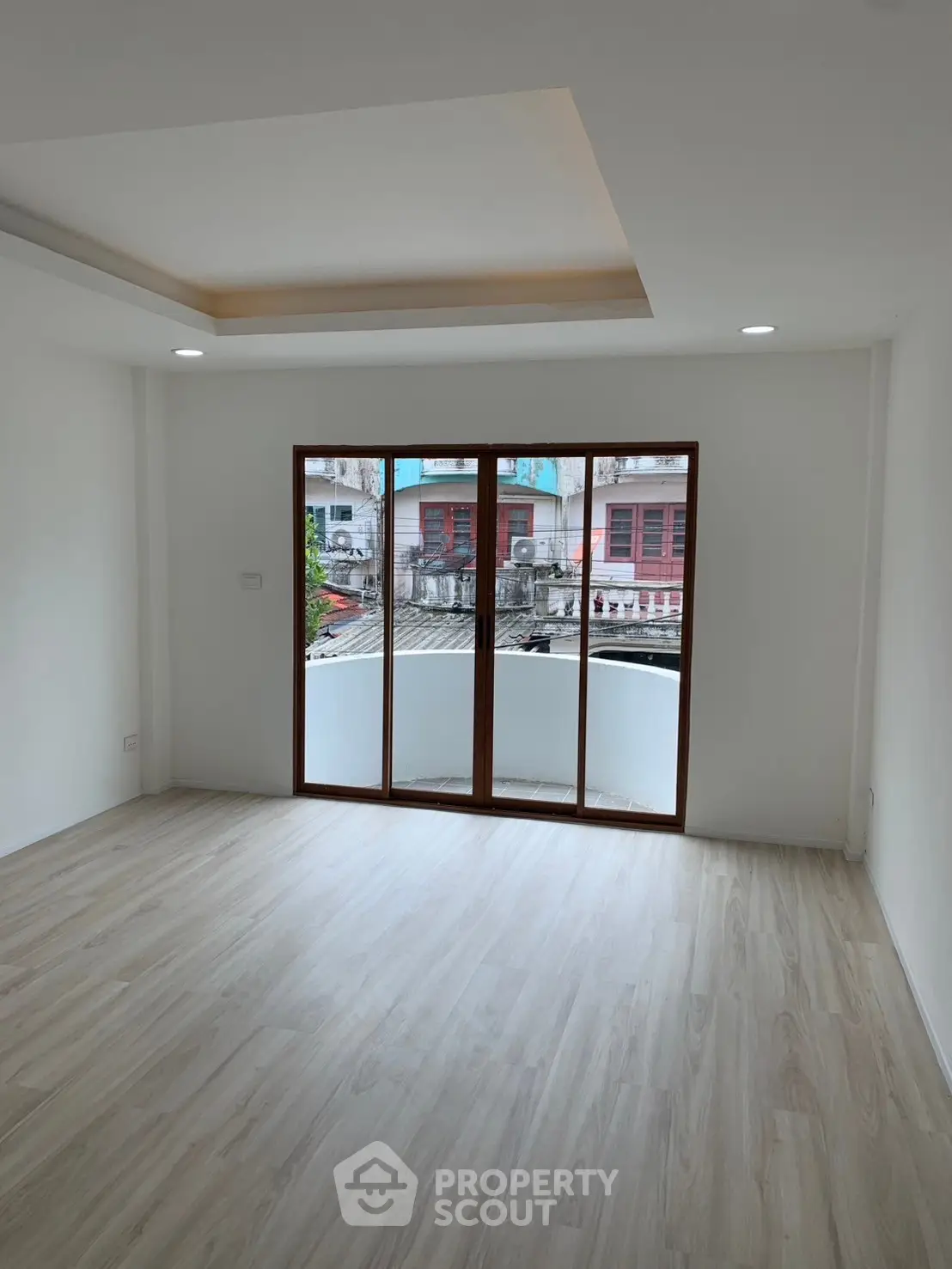 Spacious empty room with large window and wooden flooring, perfect for customization.