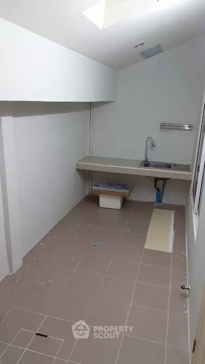 Spacious utility room with sink and tiled flooring, ideal for laundry or storage.