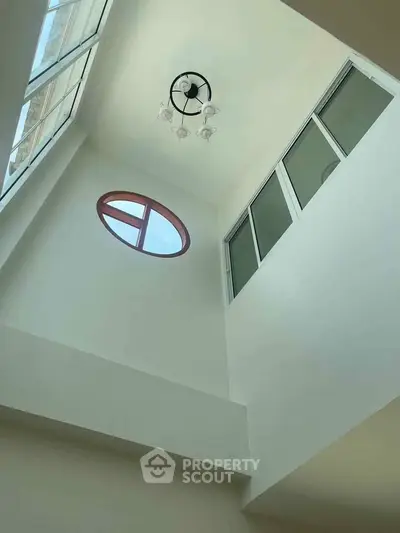 Modern architectural interior with high ceiling and unique window design.