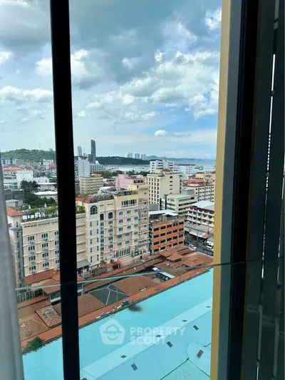 Stunning cityscape view from high-rise window with ocean in the distance, perfect for urban living.