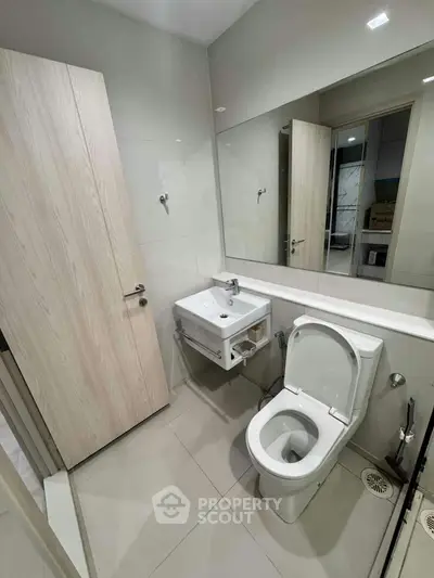 Modern bathroom with sleek fixtures and large mirror in a contemporary home.
