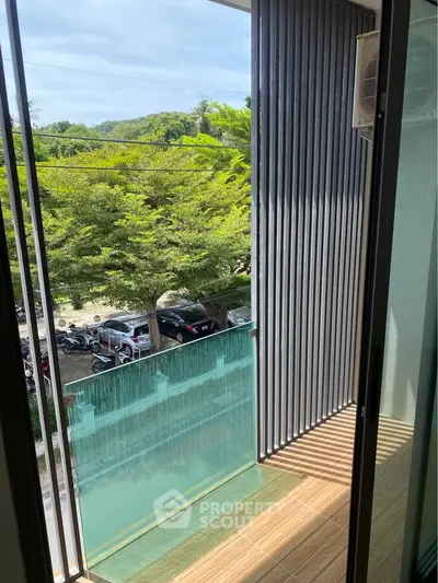 Charming balcony with lush green view and modern railing, perfect for relaxation.