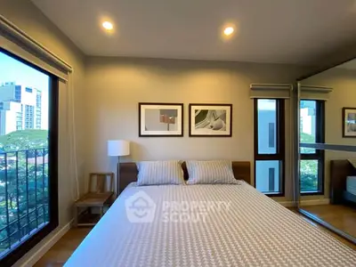 Modern bedroom with large windows and mirrored closet in urban apartment.