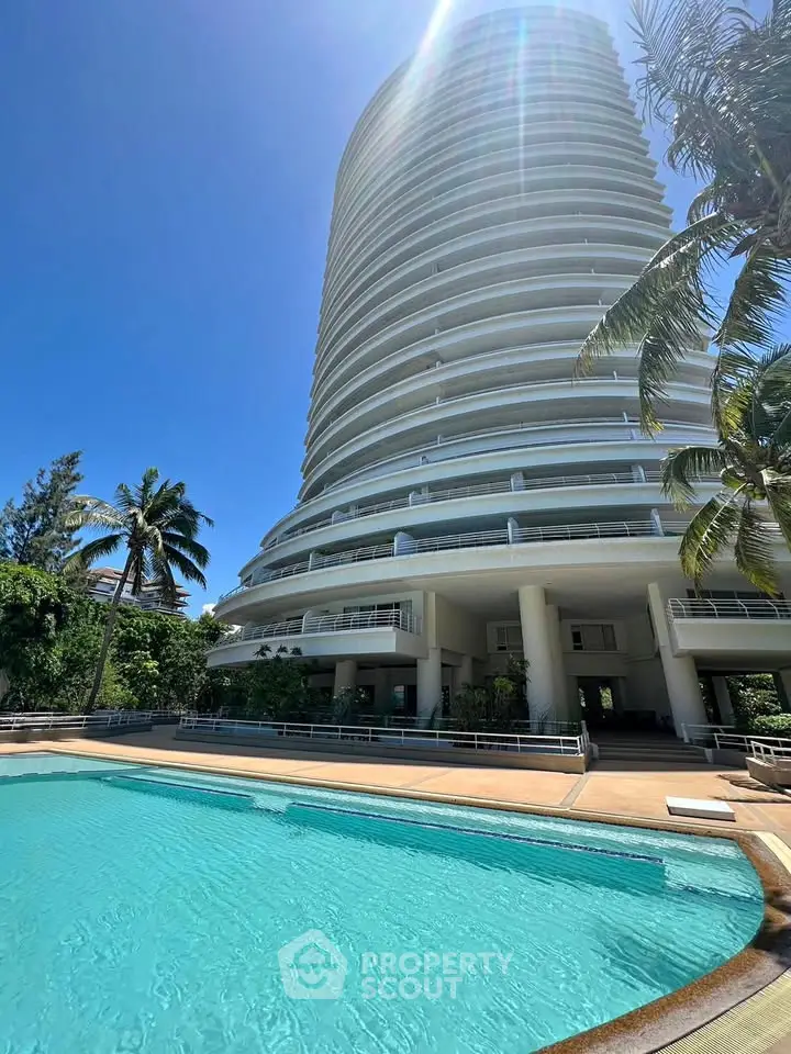 Luxurious high-rise building with a stunning pool and palm trees, perfect for upscale living.