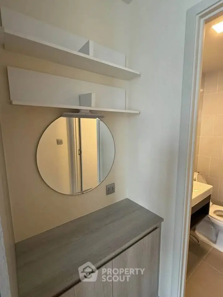 Modern bathroom with sleek vanity and round mirror, featuring minimalist design and neutral tones.