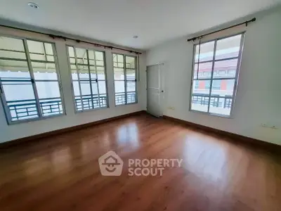 Spacious empty room with large windows and wooden flooring, perfect for customization.